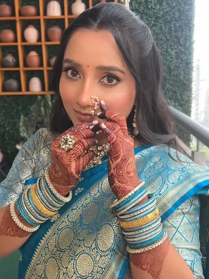 A playful and sweet shot of the bride-to-be adjusting her nath. The makeup is fresh and youthful, perfect for the happy occasion of an engagement.