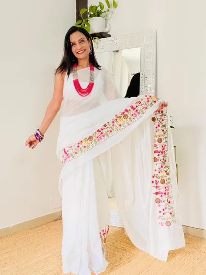 A simple and elegant white Khadi cotton saree with a colorful embroidered border. This is a versatile piece that can be dressed up or down.