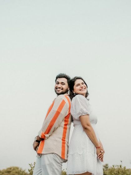 A fun, back-to-back pose against the open sky. This minimalist shot highlights the couple's happy expressions and carefree attitude.