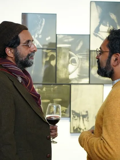 Deep in conversation over a glass of wine, an artist shares insights about his work with a guest.
