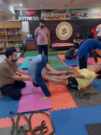 Here, I am assisting a student in a deep forward bend during a partner yoga session. This kind of support helps release the lower back and hamstrings safely.