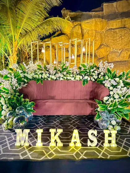 A stylish seating area for the bride and groom, featuring their combined name in marquee letters. The pink sofa and modern gold-frame backdrop create a chic and personalized photo spot. seating area.
