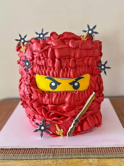 Hi-yah! This Ninjago-themed cake was for a little ninja's birthday. I used a special buttercream ruffling technique to create the red mask texture and added some fun ninja star toppers for the final touch. It's a great example of a no-fondant character cake.