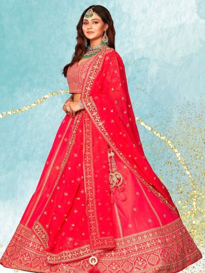 A classic red lehenga with beautiful gold embroidery and a contrasting green necklace. This studio shot highlights a timeless color combination for any bride.