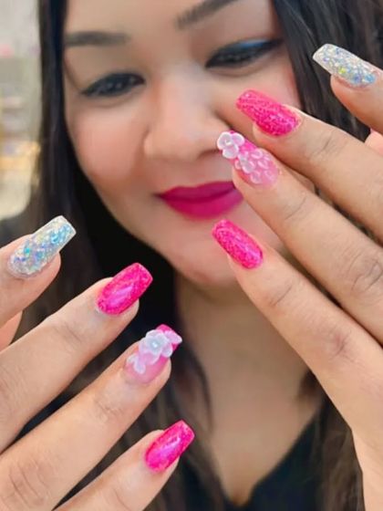 A happy client showing off her new pink glitter and 3D floral nail extensions.
