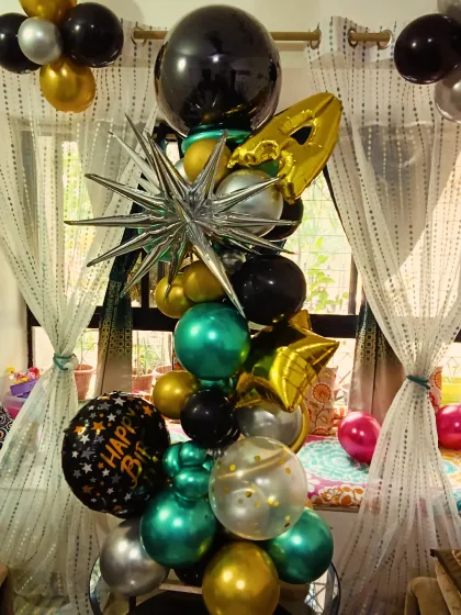 A unique and modern balloon bouquet pillar. This arrangement uses a mix of chrome, foil, and regular balloons in different shapes and sizes to create a striking decorative piece.