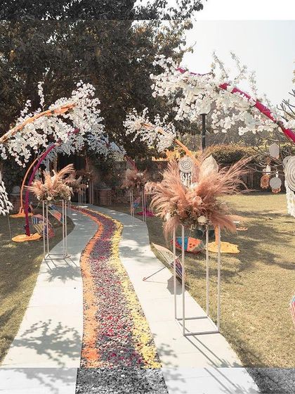 A shot of the beautiful, bohemian-themed outdoor decor for a Mehendi or Haldi function, showing the floral walkway and dreamcatchers.