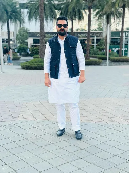 A full-length shot in a kurta-pajama and jacket in an urban plaza. My focus is always on living life to the fullest and maintaining a positive outlook.