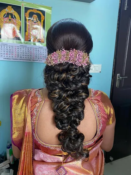A beautiful and intricate braid with a voluminous, textured finish, adorned with a pink floral accessory. This is an advanced style that is perfect for a modern bride.