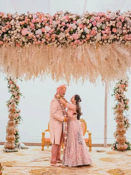 A wide shot of the couple under a breathtaking floral mandap during their Hindu wedding ceremony. This image showcases the grandeur of the decor and the intimacy of the couple's embrace.
