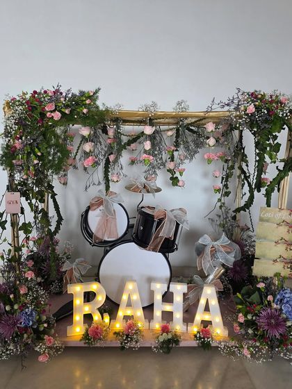 A breathtaking floral drum set created for Raha Kapoor, framed by a golden arch draped in lush greenery and hanging pink roses.