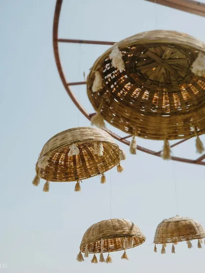 A detail of hanging decor. Woven wicker baskets with tassels are suspended from above, adding a touch of handmade, bohemian charm to the outdoor setting.