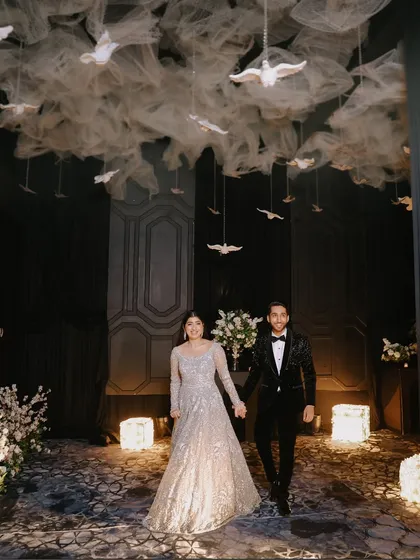 The grand entrance is a cinematic moment, and I capture it with the drama it deserves. Here, the couple makes their way into the reception under a stunning ceiling installation of white doves, setting a magical tone for the evening.