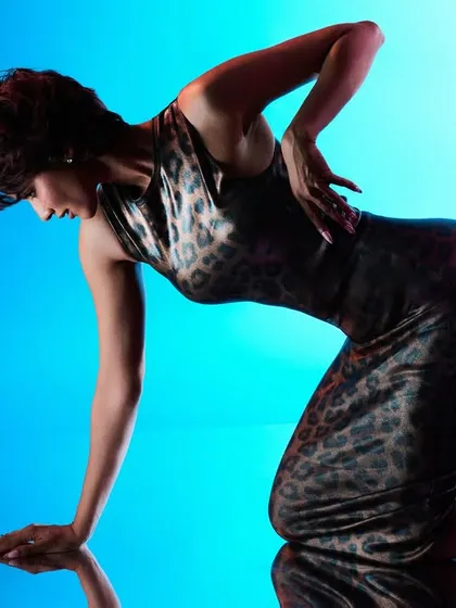 This shot uses a combination of colored gels and a hard rim light to create a dynamic, high-energy feel. The light from behind separates the model from the blue backdrop, while a magenta gel adds a pop of color to her skin.