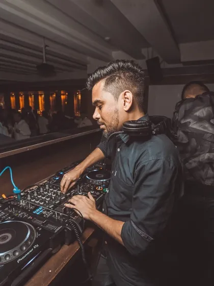 A side profile showing my concentration while mixing during a busy Saturday night set. Every transition is crafted to maintain the flow of the party.