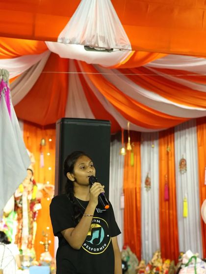 One of our students confidently taking the stage with a microphone during a performance for Ganesh Chaturthi. We provide platforms for our students to move from online practice to live public performance, helping them conquer stage fright.