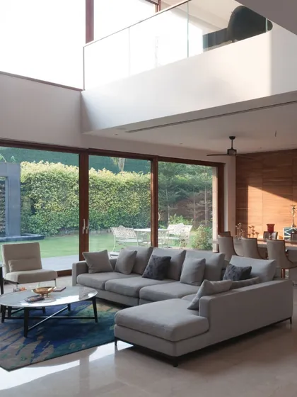 A home should be filled with light and life. This double-height living space, opening directly onto a green lawn, illustrates how we choreograph spatial volumes to create bright, airy interiors that connect seamlessly with the outdoors.