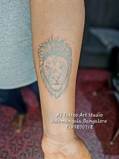A simple line work lion head tattoo on the forearm.