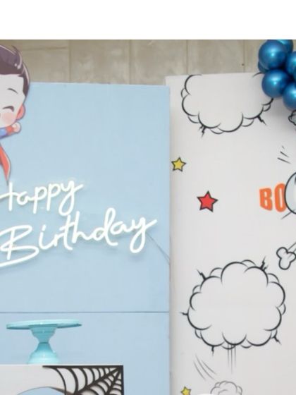 A close-up of the 'Happy Birthday' neon sign and a flying Superman cutout, adding a dynamic touch to the decor.