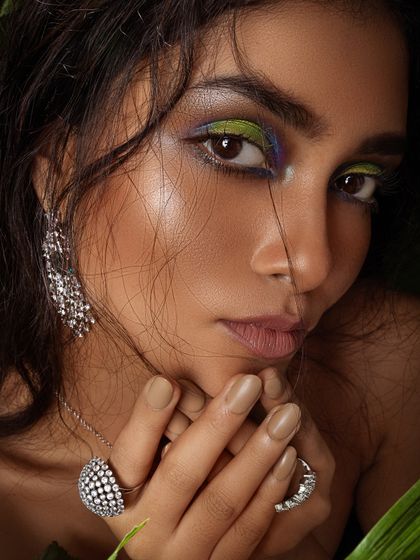 A close-up from a jungle-themed beauty shoot, featuring bold, colorful eye makeup and sparkling diamond jewelry.