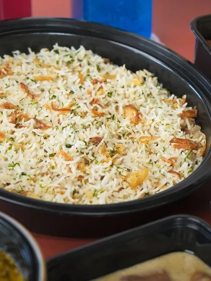 A large container of my fragrant Butter Garlic Rice, topped with fried onions and fresh herbs, a perfect accompaniment to any of my curries.