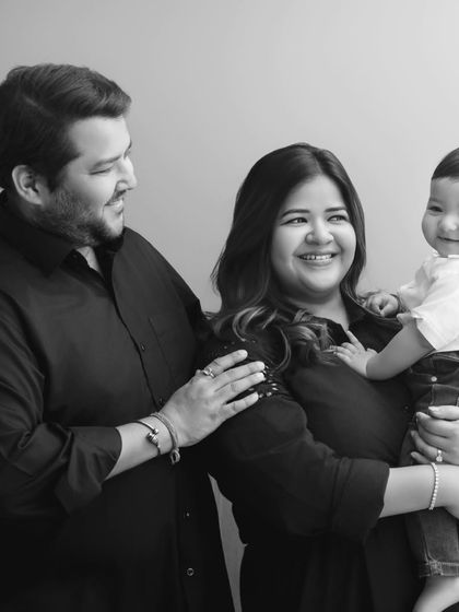 A candid moment during a black and white family session. The genuine smiles and relaxed interaction between the parents and their baby create a warm and authentic portrait.
