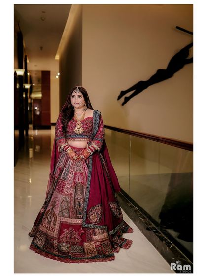 A classic bridal portrait showing off the bride's beautiful and unique lehenga in a well-lit corridor.
