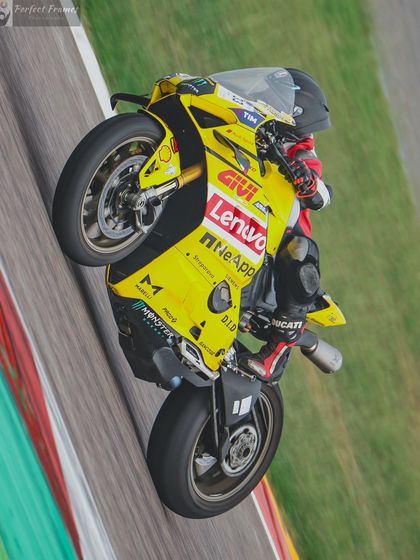 Smooth operator. A rider lifts the front wheel of a yellow Ducati Panigale while powering out of a corner, showcasing incredible throttle control.