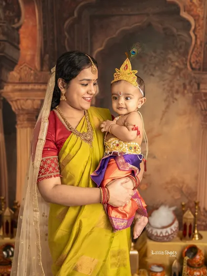 A mother and her little Krishna share a sweet moment. The baby's smile and the mother's loving gaze are the heart of this beautiful festive photo.