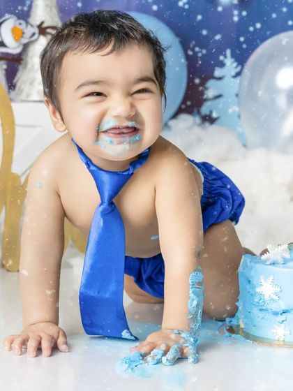 The aftermath of a fun cake smash! This little boy is covered in blue frosting and loving every second of it.
