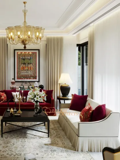A grand drawing room featuring a bold red sofa as the centerpiece, balanced by neutral tones and classic furniture. The traditional artwork and ornate chandelier complete the look of timeless luxury.