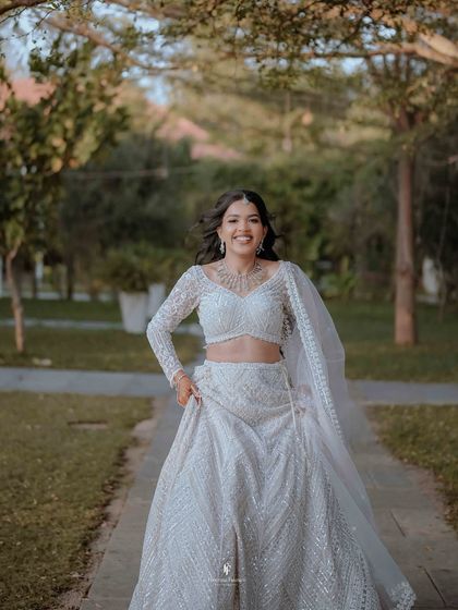 A happy, carefree shot of the bride running and smiling in her white reception lehenga.