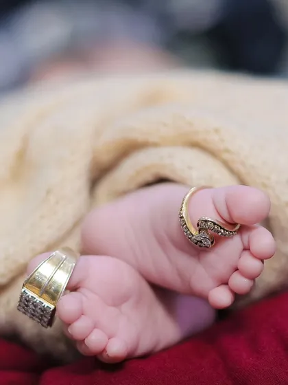 A beautiful detail shot of a newborn's tiny feet, adorned with their parents' rings. This is a sentimental way to show the scale of their new beginning.