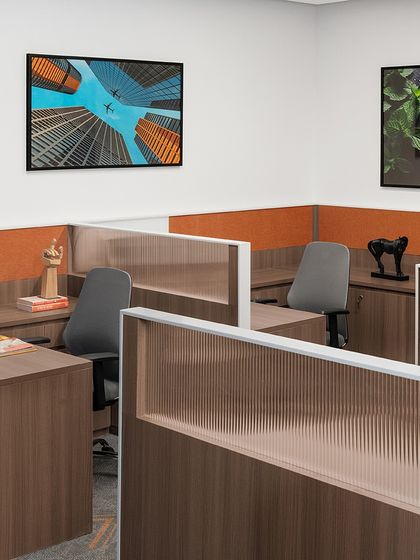Workstation cubicles at the TajSATS office, featuring fluted glass partitions and orange pinboards. The design balances the need for individual focus with a sense of connection to the larger office environment.