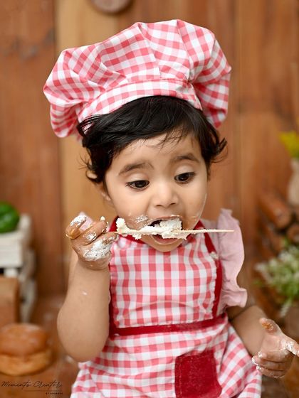 A spoonful of sweetness! This little chef is digging into her cake with gusto. The details in this bakery setup, from the rolling pin to the bread, make it an unforgettable first birthday experience.