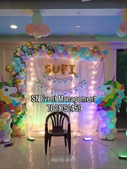 A playful unicorn-themed decoration with multiple character cutouts. The pastel balloon arch and fairy lights create a fun and magical setting for a child's party.