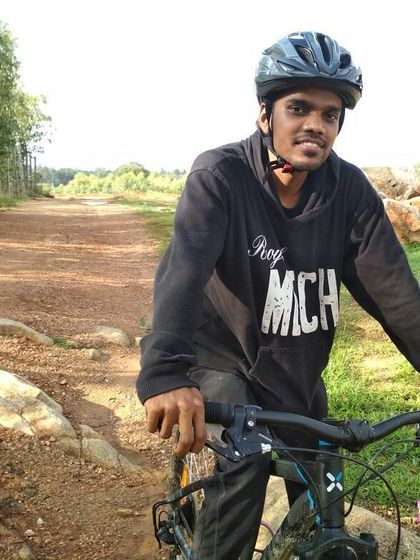 A smiling rider on his MTB, taking a moment to pause on a rocky trail during a group ride.