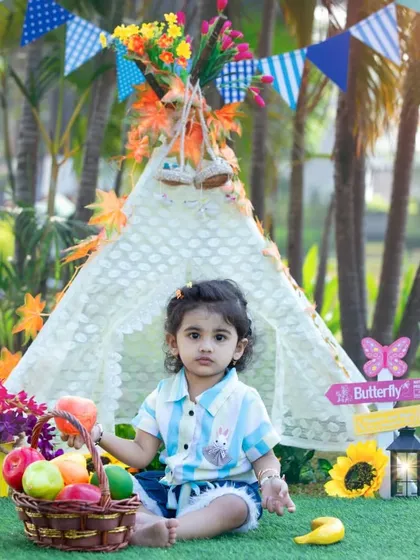 My boho teepee setup, decorated with colorful banners and flowers, creates a beautiful and festive scene for a first birthday photoshoot in the park.