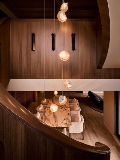 A high-angle view from the staircase overlooking the dining area. This shows how the open-plan space is connected vertically, with the lighting fixture acting as a visual link.