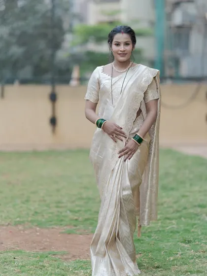 A full-length shot of the new mother at the naming ceremony, looking graceful in a beautiful off-white silk saree.