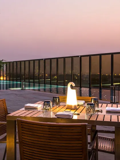 As the sun sets, our rooftop tables offer a breathtaking view. It's the perfect setting for an alfresco dinner, where you can dine by the pool under a twilight sky.