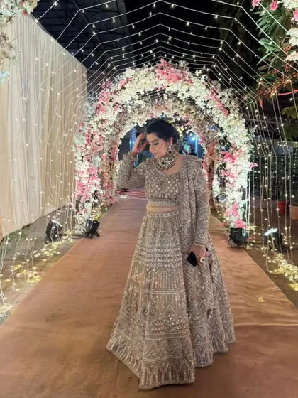 Making an entrance through a tunnel of lights, our client looks like a star in this embellished beige lehenga. A perfect rental for a grand reception.