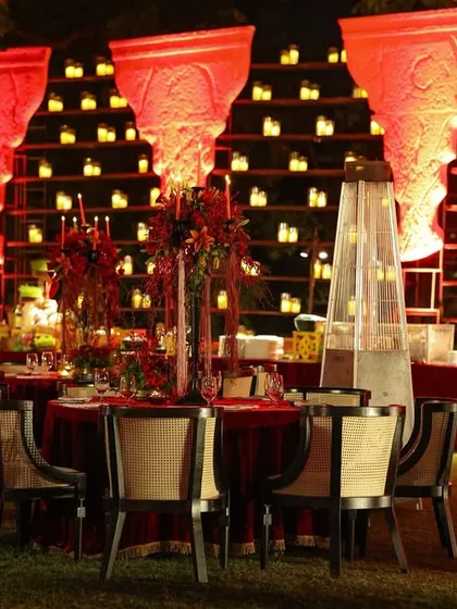 For this outdoor Sangeet, the dining area was set against a dramatic backdrop of tiered candle walls, with red uplighting creating a warm and vibrant atmosphere.
