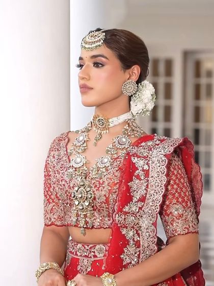 This profile shot showcases the heavy layered necklace and the detailed embroidery on the blouse, key elements of a grand bridal look.