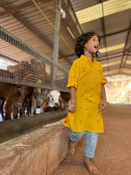 Teaching our kids to be kind to every being is so important. This little one is wearing our yellow kurta while visiting a goshala, looking comfortable and connected to nature.