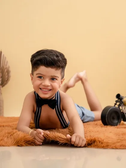 A bright, happy smile from this young boy as he lies on a fuzzy rug, a simple and joyful portrait.