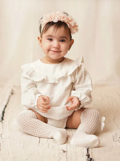 A happy, smiling baby sitting up and clapping. This is a perfect portrait from a sitter session, full of joy and personality.