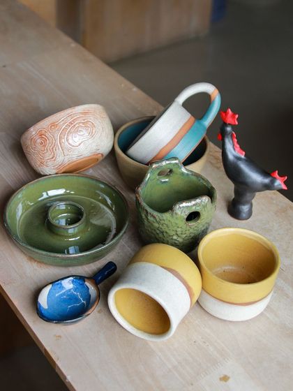 A playful assortment of student work, including a rooster figurine, a hanging planter, and a donut shaped candle holder.