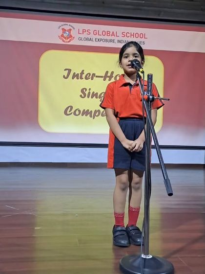 Dressed in her house color, a student delivers a melodious performance at the singing competition. These inter-house events foster a healthy competitive spirit and house pride.