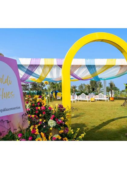 The main entrance to the Haldi lawn, with a bright yellow arch and a colorful draped canopy.
